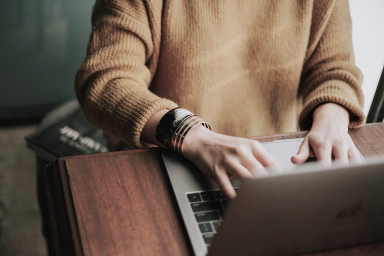 Unsere Arbeitsweise Eine Person sitzt am Schreibtisch und tippt am Laptop. Man sieht nur den Oberkörper und die Arme.